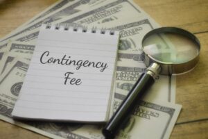 Contingency fee agreement concept with notebook labeled contingency fee, magnifying glass, and U.S. dollar bills representing California personal injury lawyer fees.
