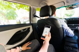 Rideshare passenger using mobile app in car backseat during trip, illustrating legal rights after a rideshare accident