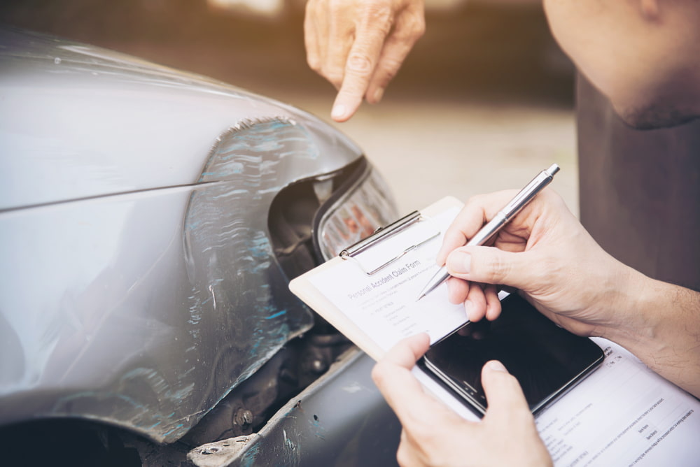 Person documenting damage to a car after a traffic accident.