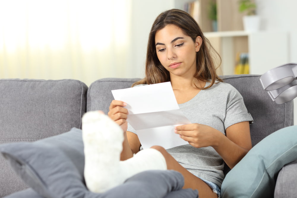 Person with a leg cast reviewing paperwork while recovering at home.