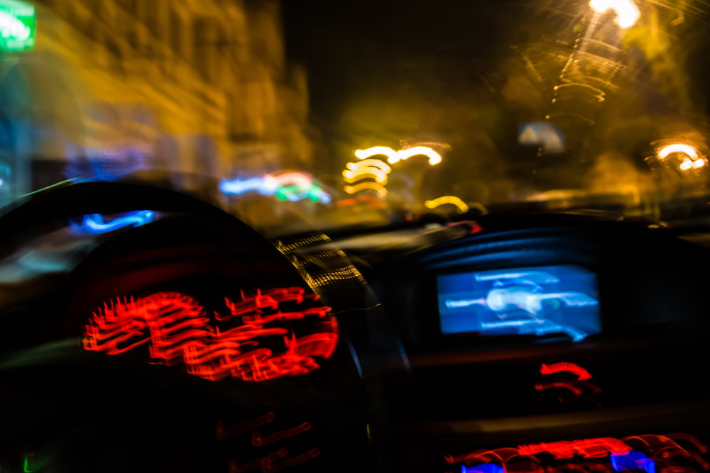 blurred view from inside a moving car at night with dashboard lights glowing