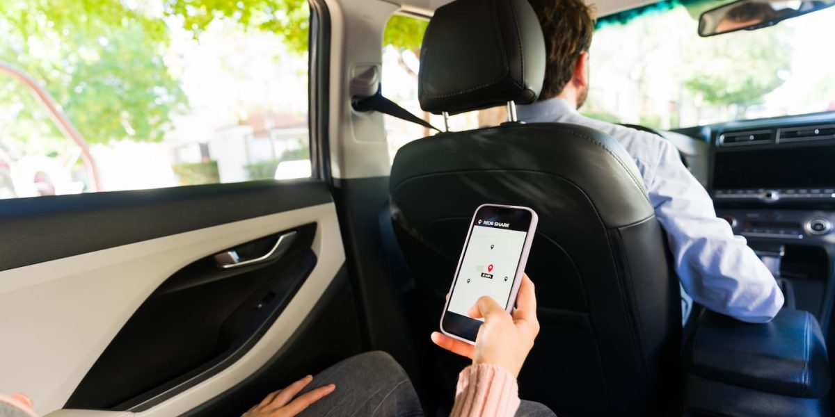 Rideshare passenger using mobile app in car backseat during trip, illustrating legal rights after a rideshare accident